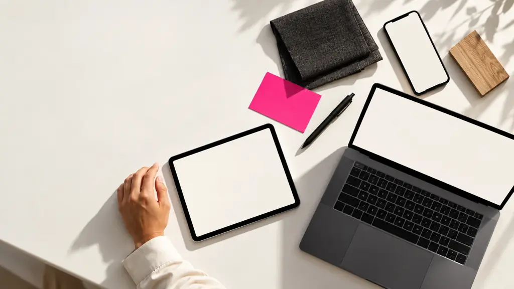 Celular, agenda digital e computador na mesma mesa de trabalho.