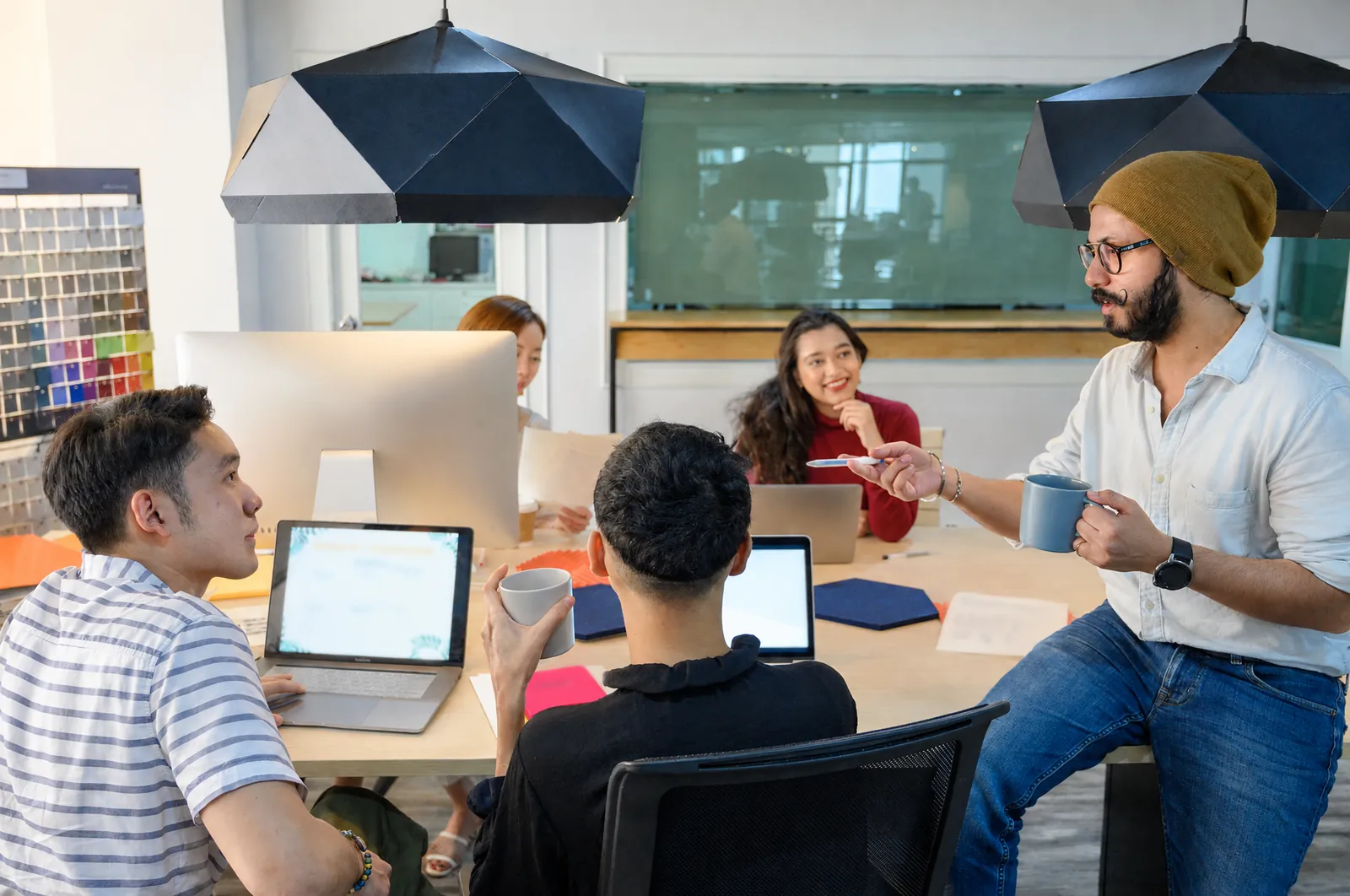 A small team in a training session: one person explains while the others work on their computers.
