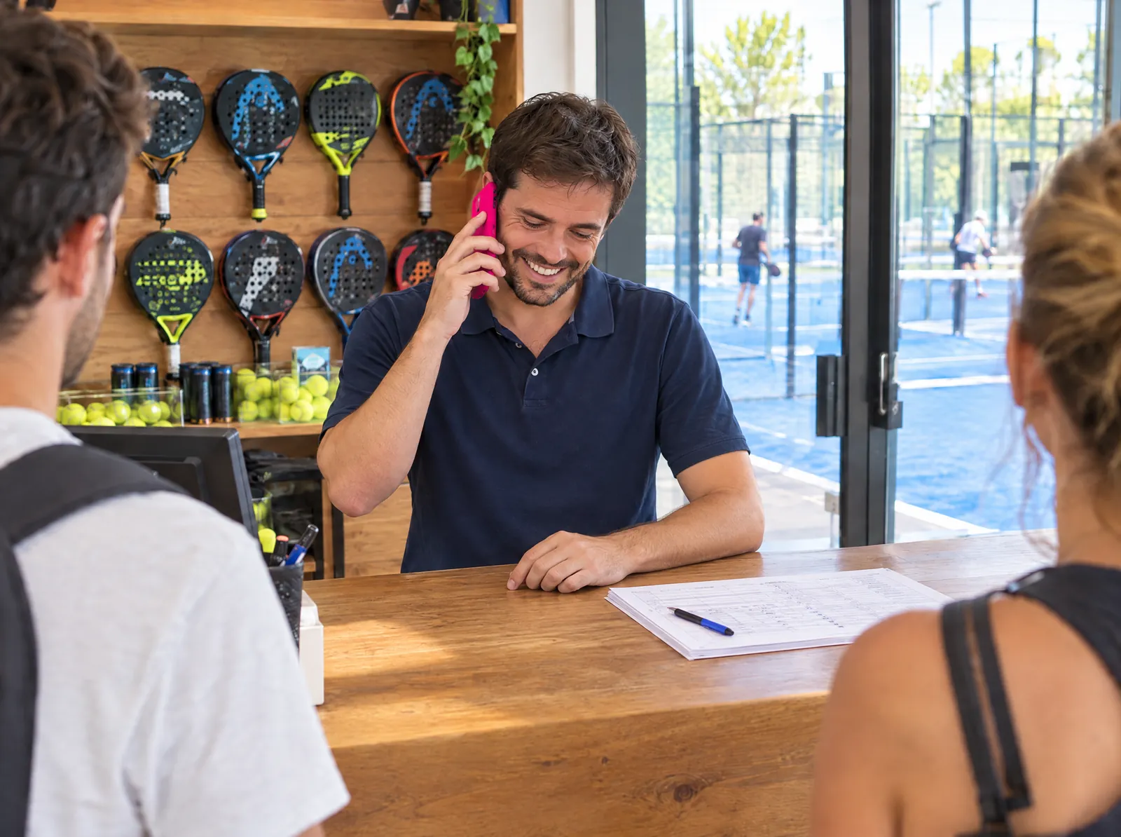 Com a Sapiens: o mesmo recepcionista fala ao telefone rindo, com o balcão organizado.