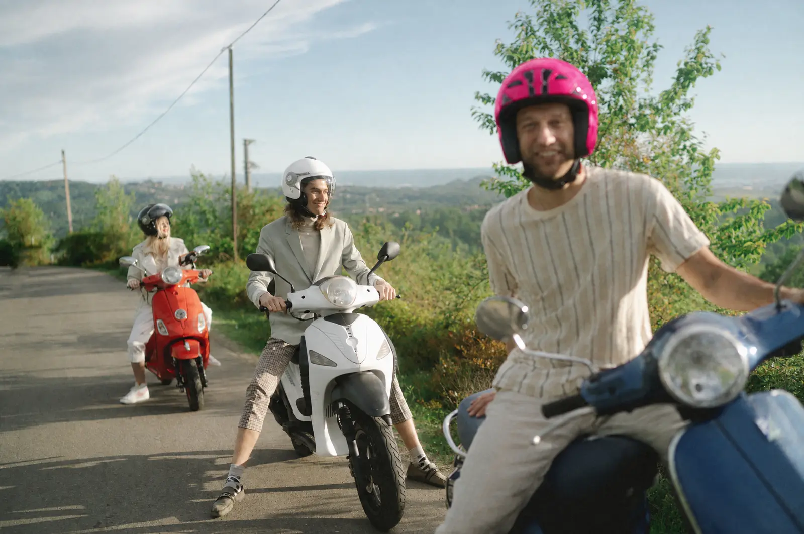 Aluguel de motos: um grupo de amigos sai para passear de scooter; um deles usa capacete fúcsia.